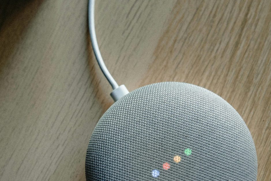 A top view of a smart speaker with a glowing indicator on a desk, emphasizing modern technology.